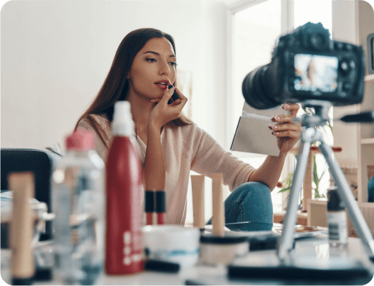 brand ambassedors Beauty influencer applying lipstick while filming a makeup tutorial in front of a camera setup.