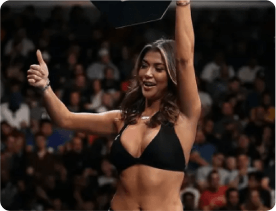 vip promoters Ring girl in a lively arena holding up a round card and giving a thumbs-up.